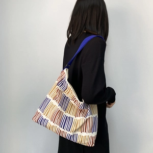 Detail view of large striped canvas tote bag with vibrant blue wide shoulder strap