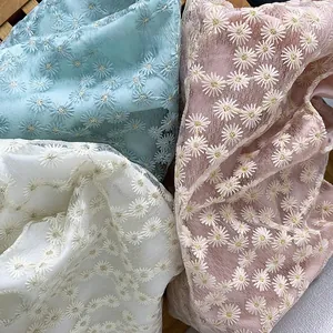 Detail of floral daisy embroidery on semi-transparent organza fabric in three colors