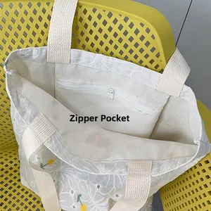 Close-up of the interior zipper pocket on a white canvas tote bag with daisy embroidery