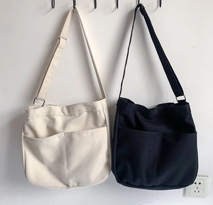 Detail view of durable canvas crossbody bags with front pockets in black and cream white