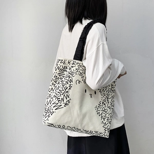 Detail of canvas tote bag with black cartoon prints and stylish ruched shoulder straps