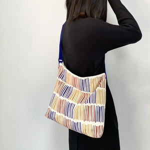Detail view of colorful geometric wave patterns and adjustable blue strap on canvas bag