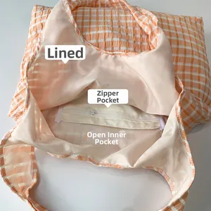 Detail view of large checkered canvas tote bag showing inner zipper pocket and lining