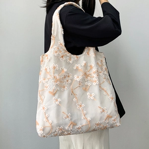 Close-up of mesh lace canvas tote bag with delicate orange floral embroidery details