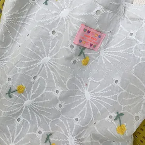 Close-up of white floral embroidery on lace canvas bag with small pink woven label detail