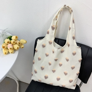 Detail of white canvas tote bag with 3D tulip embroidery and integrated handles