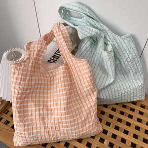 Detail of checkered tote bags in orange and green with pleated seersucker texture