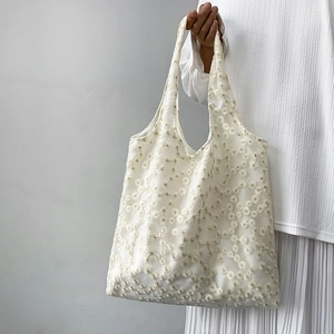 Close-up of white lace embroidery canvas tote bag with delicate daisy floral patterns