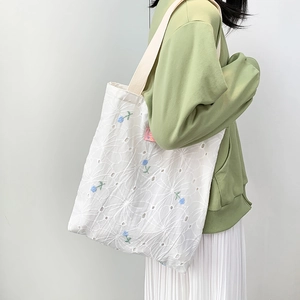 White canvas tote bag with blue flower embroidery and cut-out pattern for women