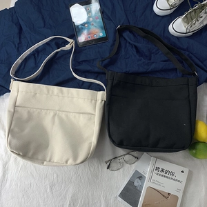 Close-up of minimalist canvas crossbody bag with front pocket and adjustable shoulder strap