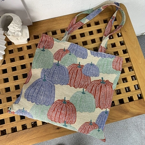 Close-up of woven pumpkin jacquard fabric on a retro tote bag with red and green patterns