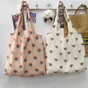 Detail view of canvas tote bags with 3D tulip floral patterns in soft apricot and cream colors