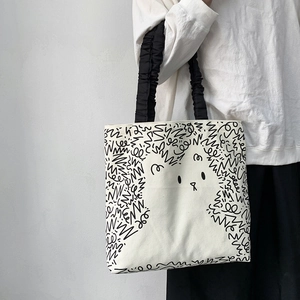 Detail of white canvas tote with rabbit doodle print and ruffled black handle