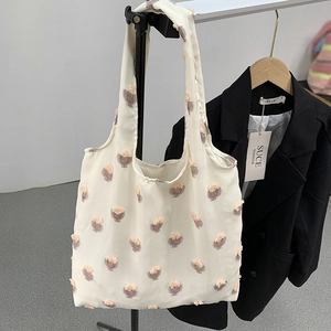 Off-white canvas tote bag featuring pink tufted 3D flowers and spacious shoulder straps