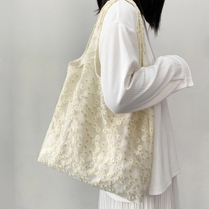 Detailed close-up of white lace tote bag with delicate daisy embroidery and mesh texture