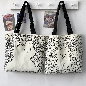 Detail of canvas tote bags with cute cartoon cat and dog prints and ruffled black straps
