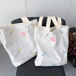 White canvas tote bag with floral daisy embroidery and handmade woven label