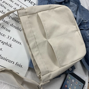 Minimalist cream canvas crossbody bag with large front pockets and adjustable strap