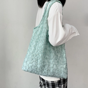 Detail view of mint green mesh tote bag with white daisy embroidery on fabric