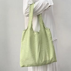 Detail of mint green tote bag featuring textured leaf patterns and soft woven fabric