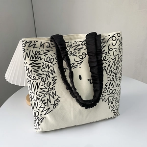 Close-up of cream canvas tote bag featuring black minimalist cartoon cat print and ruffled straps