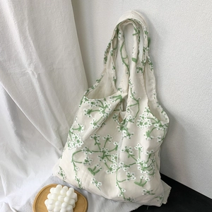Close-up of off-white canvas tote bag with green floral embroidery in a home setting