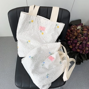 Detail view of floral embroidery on a white canvas tote bag with heart label
