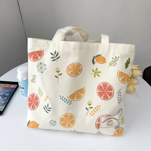 Detail of canvas tote bag featuring fresh orange slices and floral pattern with woven label