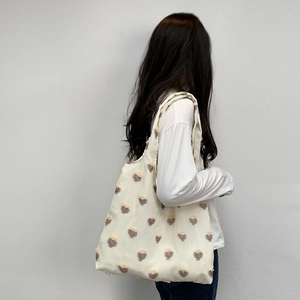 Detail of a large canvas tote bag with 3D floral embroidery shown on shoulder