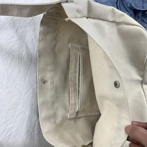 Detail view of cream canvas bag interior showing zipper pocket and magnetic snap closure
