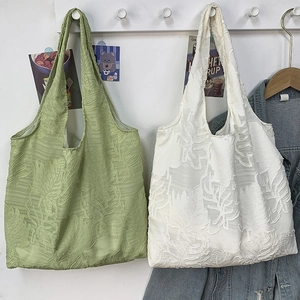Detail showing the textured leaf jacquard fabric of light green and beige tote bags