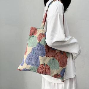 Detailed texture of woven pumpkin embroidery on beige jacquard tote bag fabric
