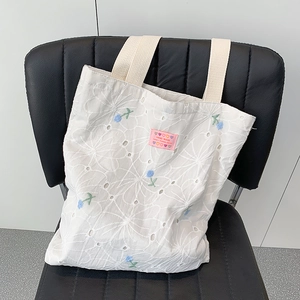 Detail of floral embroidery on a white canvas tote bag with a pink decorative label