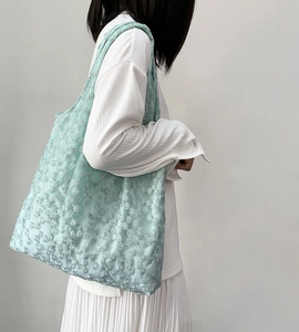 Detail of light green floral embroidery on the shoulder tote bag with daisy patterns