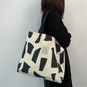 Close-up of a large beige canvas tote bag with black geometric patterns and cartoon rabbit