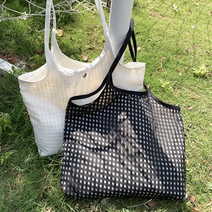 Outdoor close-up of checkered mesh tote bags with silver snap button in black and white
