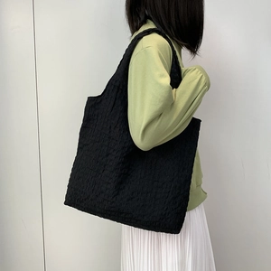 Detail of black quilted canvas tote bag with textured bubble fabric shown on shoulder