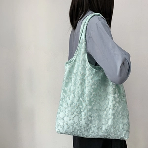Close-up of mint green canvas tote bag with white daisy floral embroidery and wide strap
