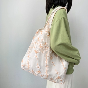 Detail of floral embroidery on a white mesh tote bag showing fine craftsmanship