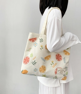Detail of canvas tote bag featuring fresh fruit print and stitched fabric label on front