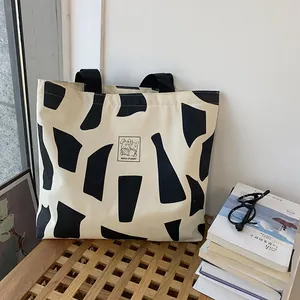 Detail of canvas tote bag featuring rabbit reading print and black geometric patterns