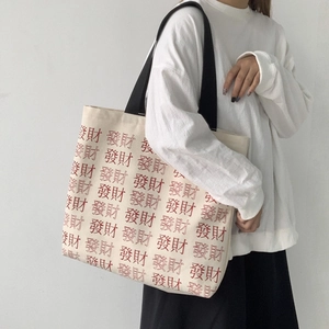 Detail of a large canvas tote bag featuring red Chinese character print and black straps