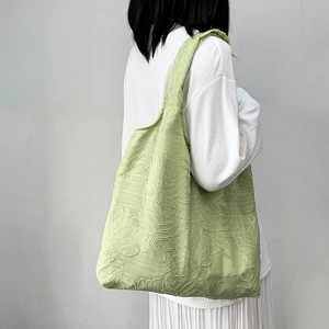 Detail of light green shoulder bag with 3D leaf jacquard texture and wide strap