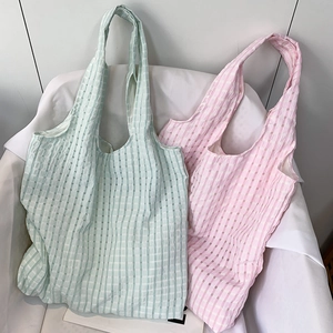Detail of mint green and pink checkered canvas tote bags with textured fabric on a chair