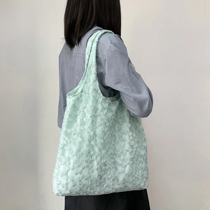 Detail of mint green mesh tote bag with white daisy embroidery and wide shoulder strap