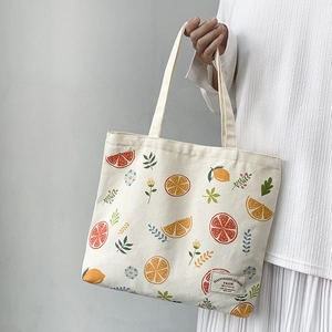 Close-up of fruit and floral print on canvas tote bag with woven happiness label