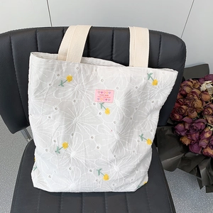 Detailed embroidery view of floral canvas tote bag on a black leather surface