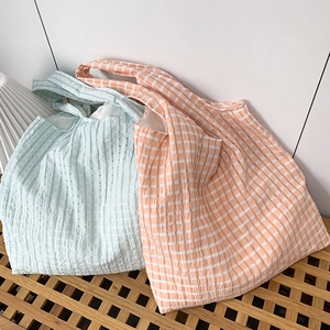 Detail of checkered seersucker tote bags in mint green and peach with textured fabric