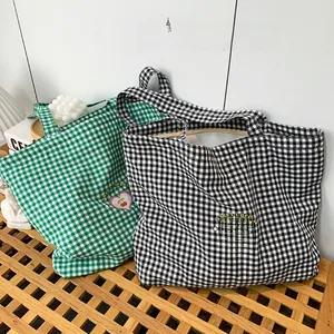 Détail de sacs cabas en toile à carreaux rouge-blanc et vert-blanc et broderie cerise