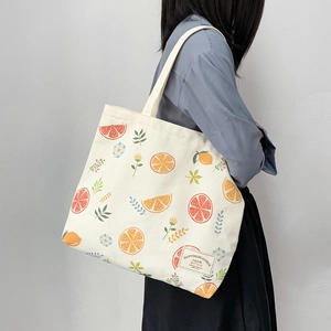 Detailed macro view of cream canvas tote featuring vibrant citrus and floral patterns